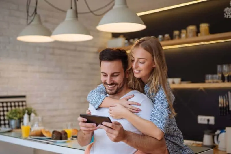 smilling couple looking at phone in kitchen