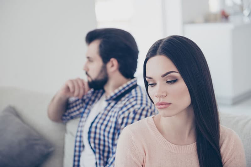 thoughtful woman sitting beside man at home