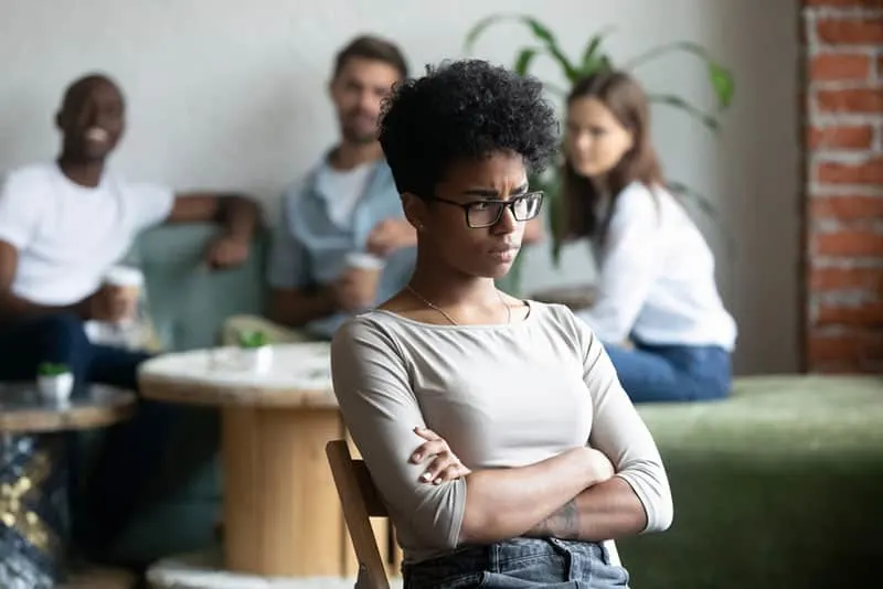 upset woman sitting in front of smiling friends