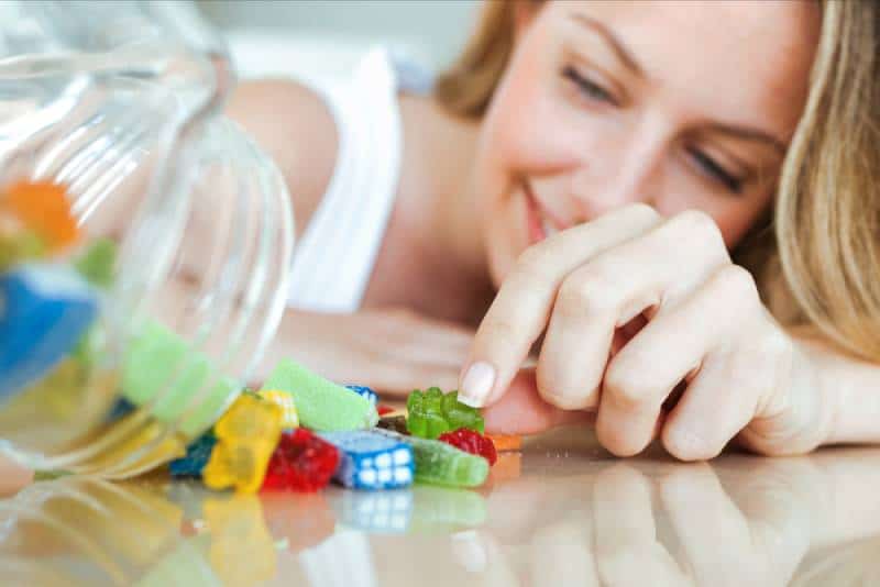 mujer comiendo caramelos de colores en casa