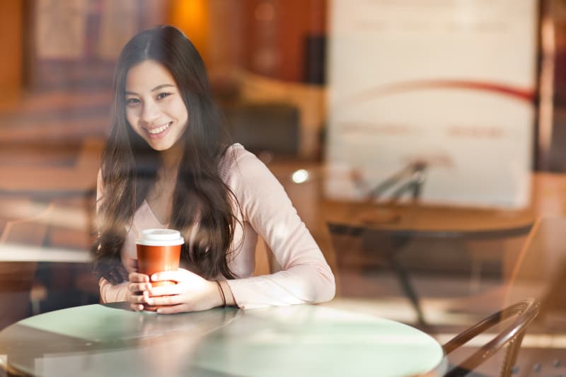 woman holding cup of coffee in cafe