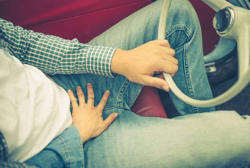 woman put hand on man jeans in car