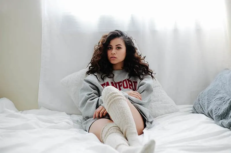 woman with long socks leaning on pillow on bed