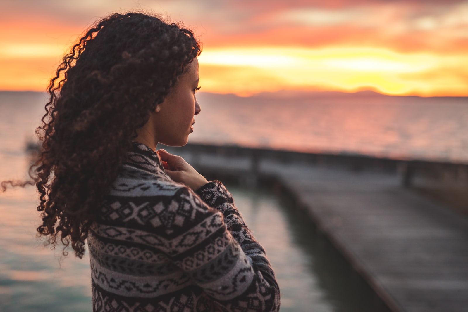Young African American woman is standing on the promenade at the lake