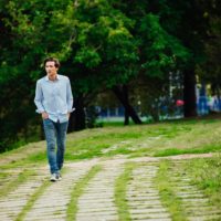 a man in a blue shirt walks through the park