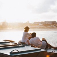 back view of couple sitting beside water