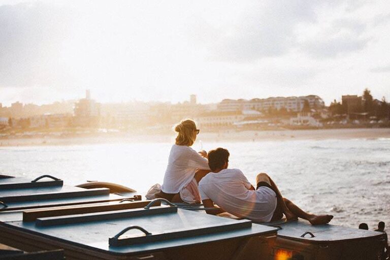 back view of couple sitting beside water