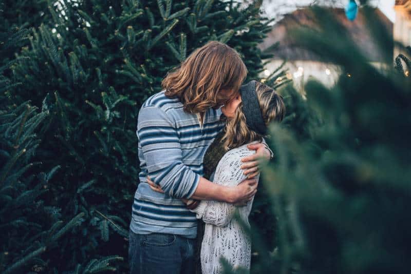 L'uomo bacia la donna vicino all'albero di pino 