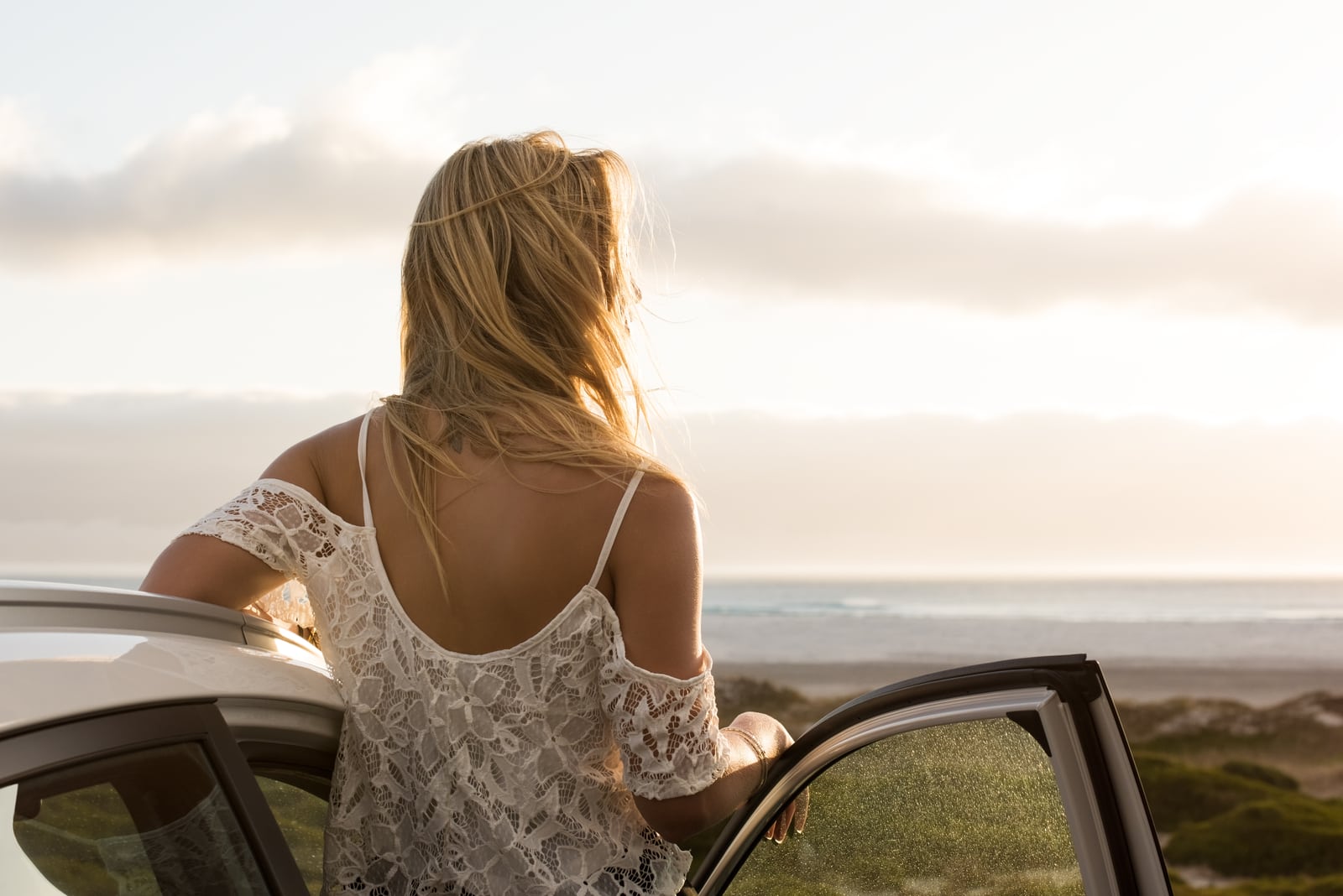 Serene woman leaning on car during sunset