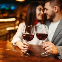 coppia con bicchiere di vino in mano al bar