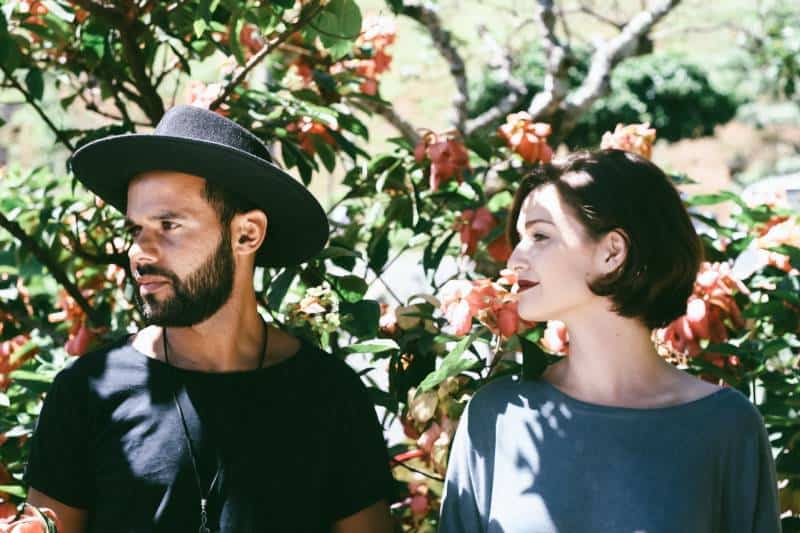 Woman stands next to man with black hat