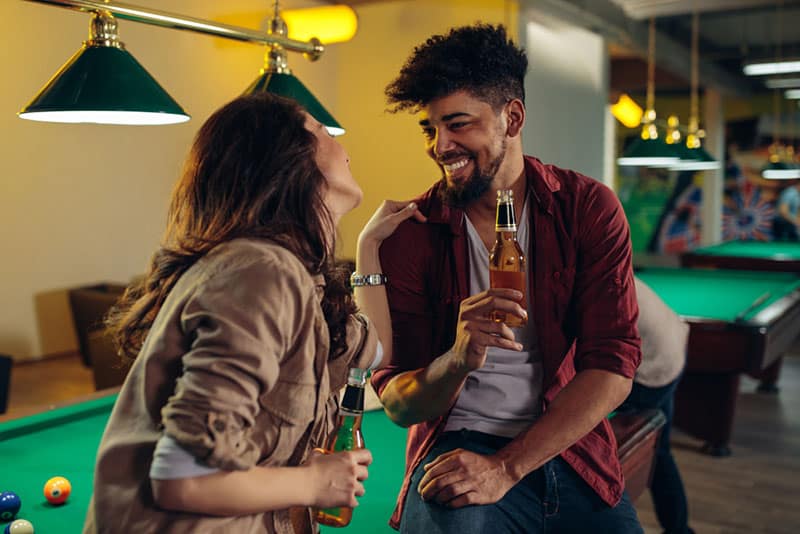 pareja bebiendo cerveza en mesa de billar