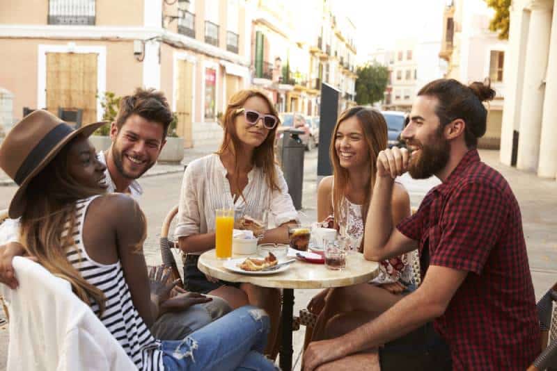 amigos a divertirem-se sentados num café de rua