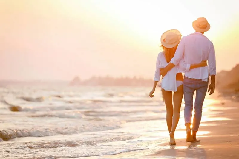 happy couple walking on seashore