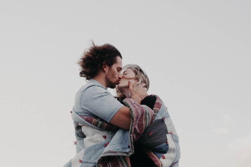 man and woman kissing each other outside