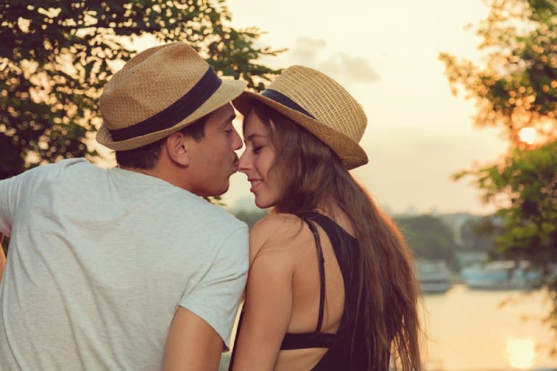 man kissing his girlfriend's nose in nature