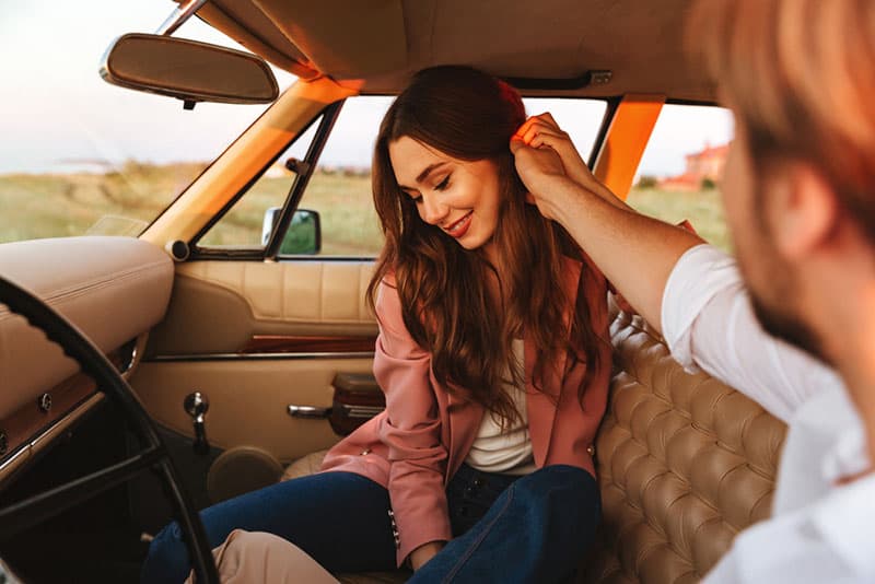 homem a tocar no cabelo de uma mulher no carro