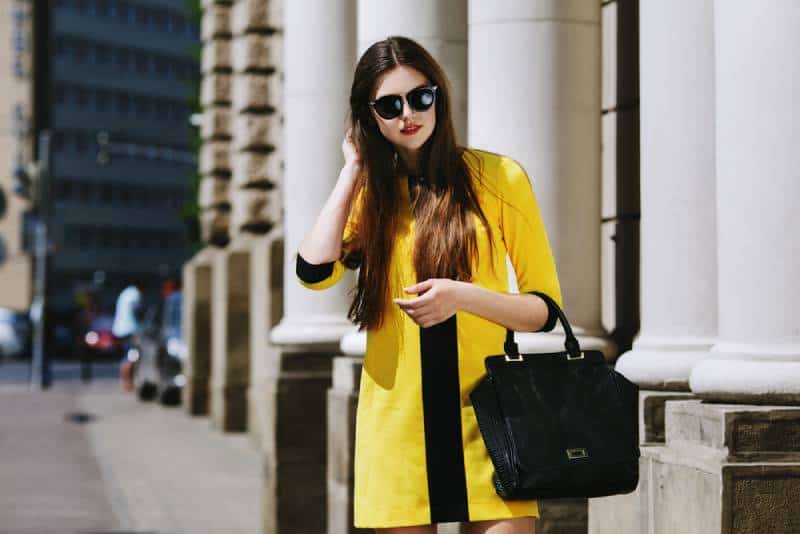 portrait of young lady in yellow jacket standing on street