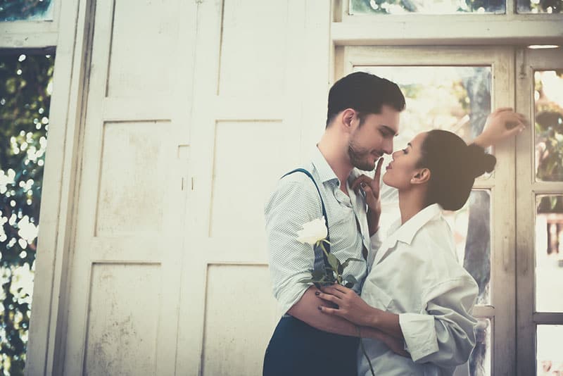 romantic couple looking each other outside beside door