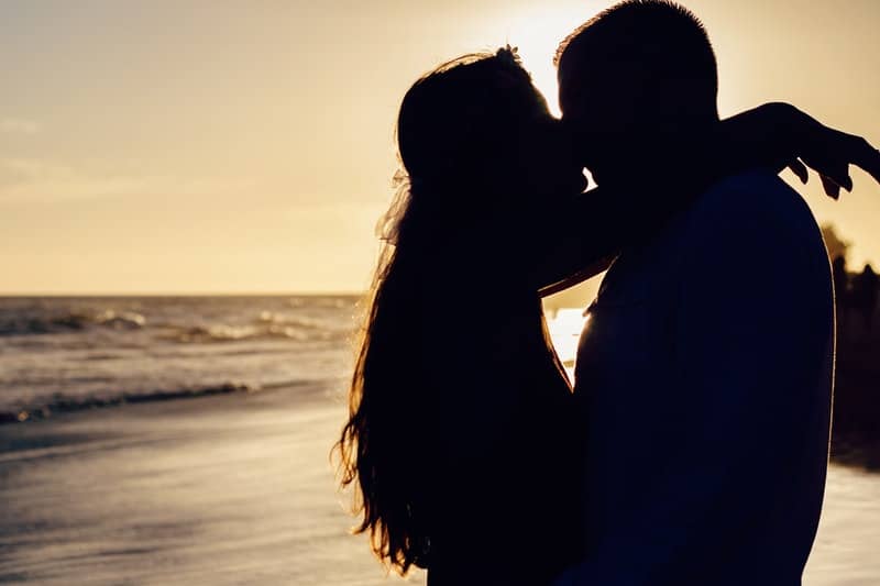 silueta de pareja besándose junto al mar