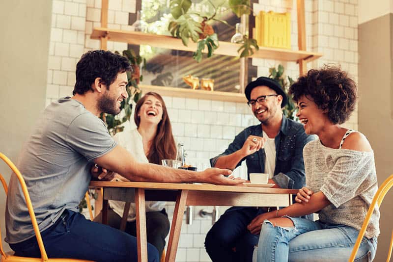 amigos sonrientes conversando positivamente en un café