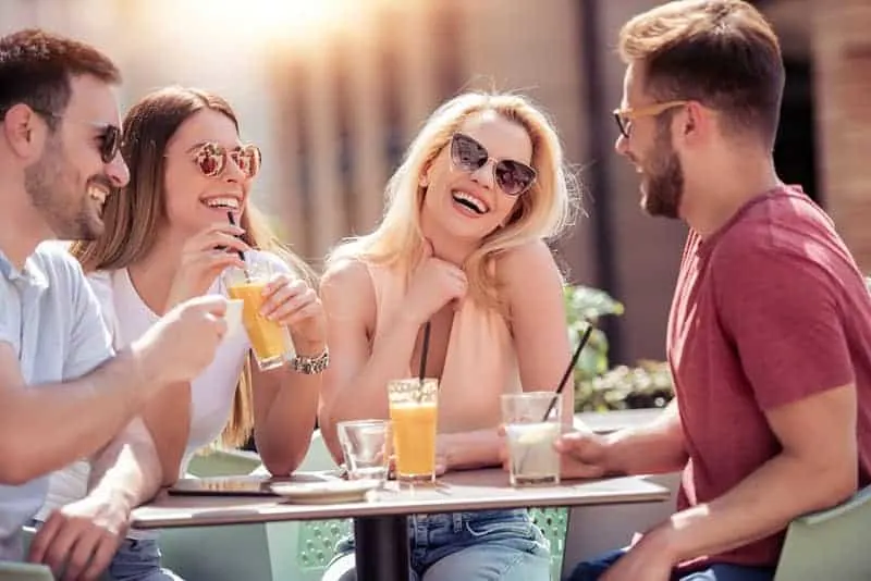smiling friends sitting at street cafe