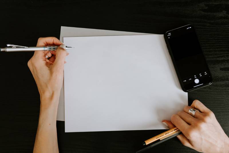 manos de mujer con bolígrafos y papel sobre la mesa