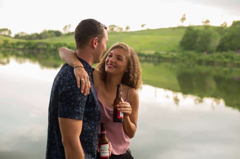 mulher a segurar uma garrafa de cerveja enquanto abraça um homem