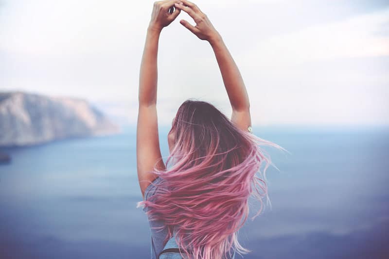 woman raising her hands in front of sea