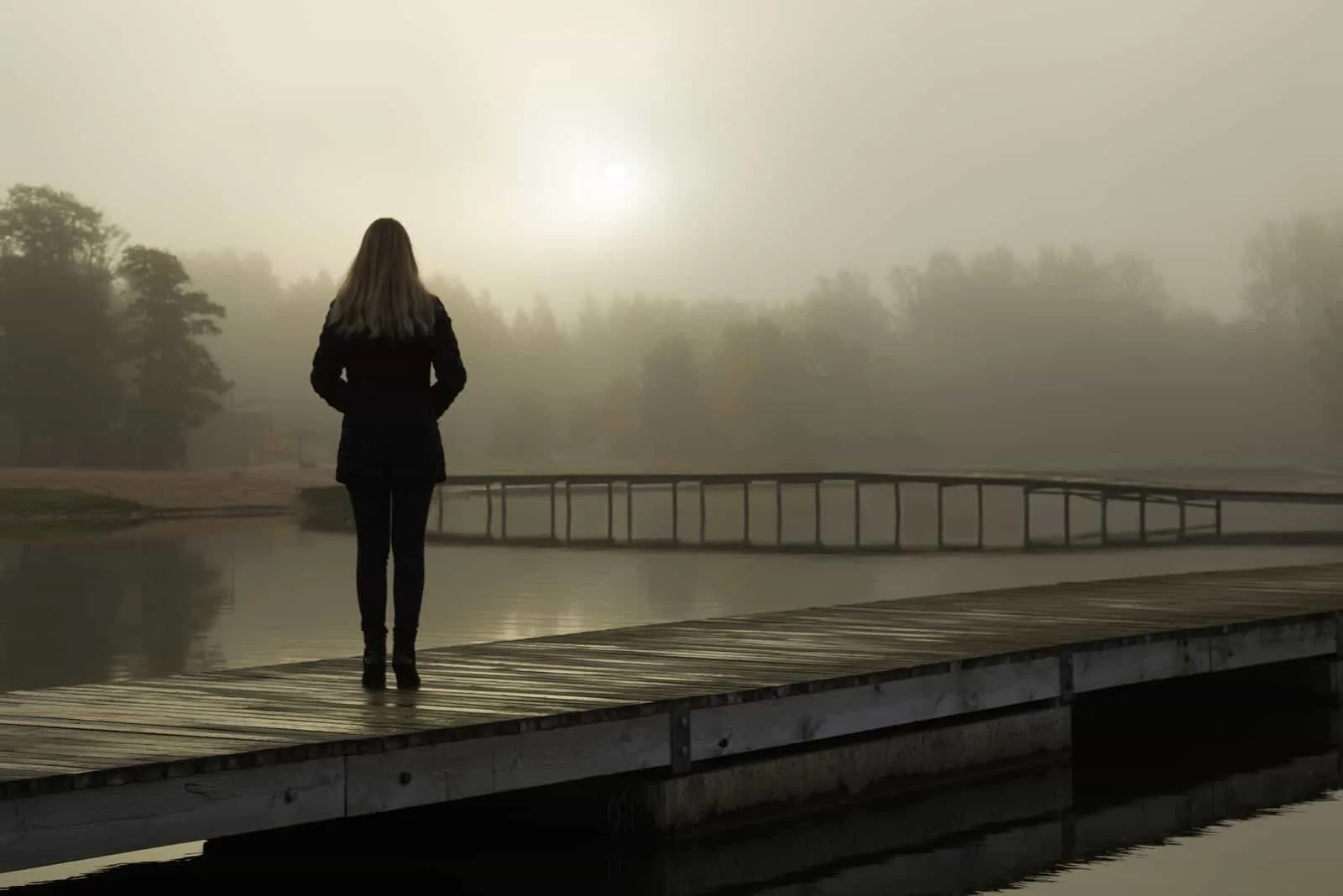 woman standing alone on lake footbridge