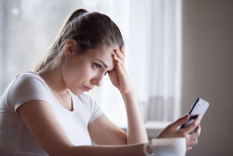 worried young woman looking at phone