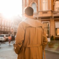 a man in a beige coat walks down the street