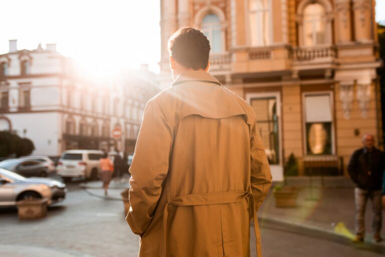 a man in a beige coat walks down the street