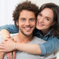 smiling woman hugging man from back