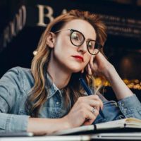 thoughtful woman wearing glasses at cafe