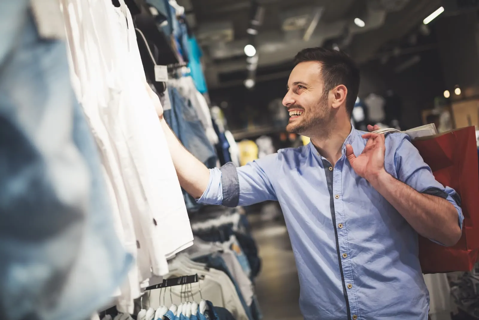 a smiling man in shopping looking at shirts