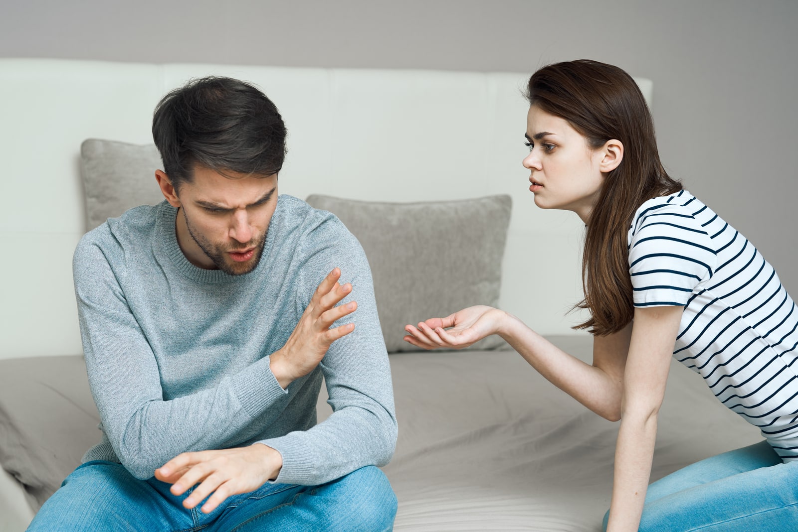 angry man arguing with woman on the bed