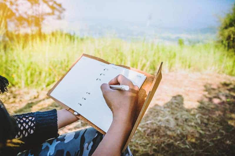 primer plano de un hombre escribiendo en un cuaderno