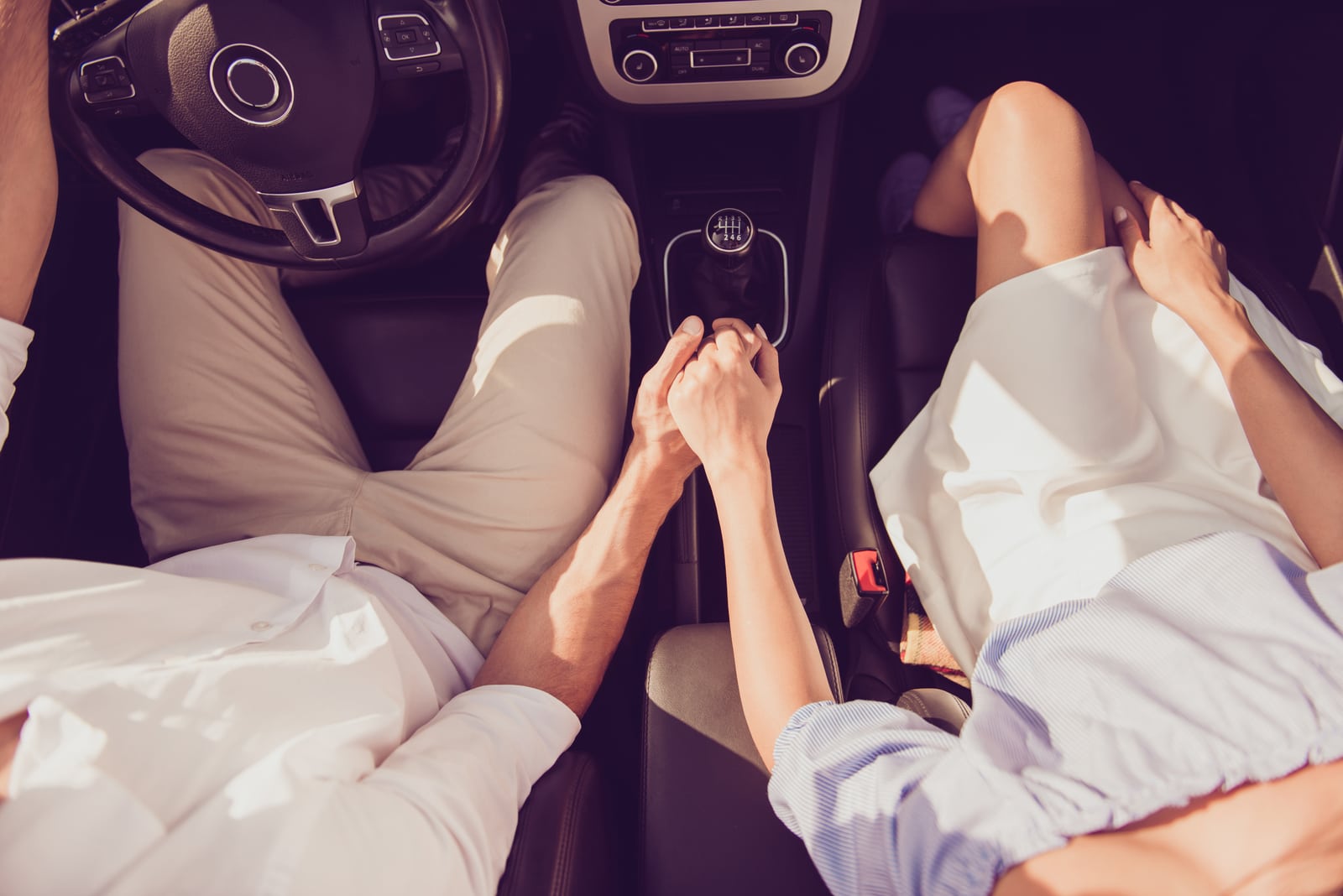 pareja sentada en coche cogida de la mano