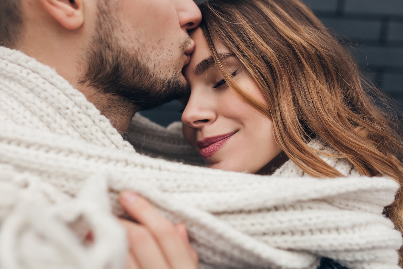 man kissing woman on the forehead