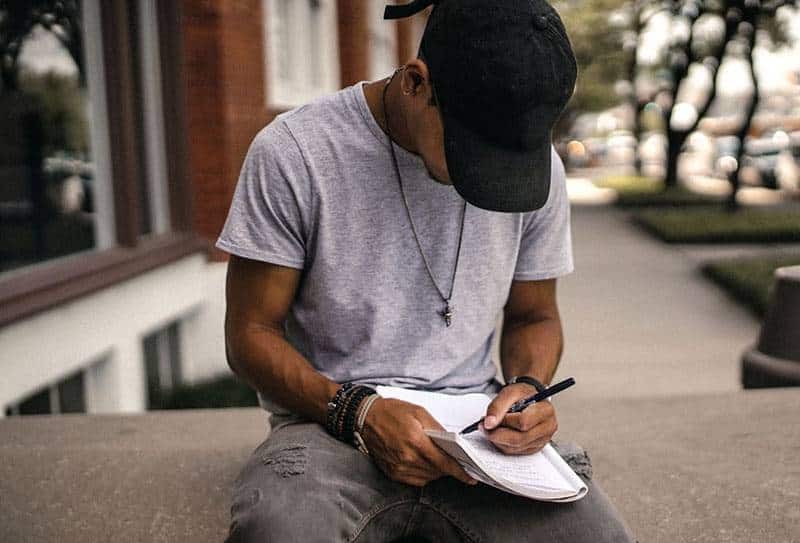 hombre con sombrero negro escribiendo en un papel