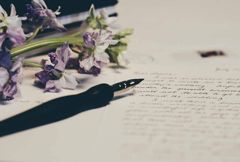 foto di penna stilografica su carta accanto a un fiore