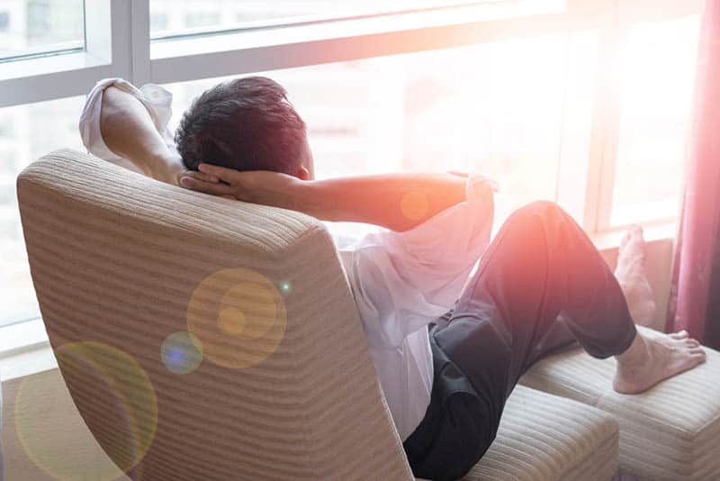 uomo rilassato seduto accanto alla finestra e che guarda fuori