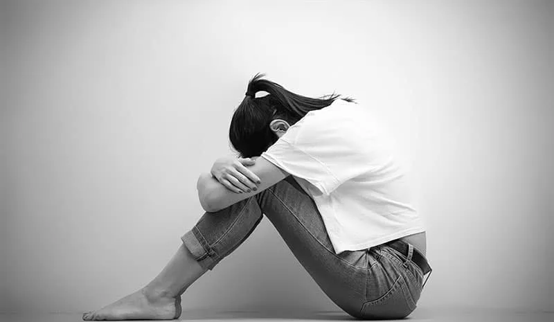 sad woman hug her knee and cry in monochrome