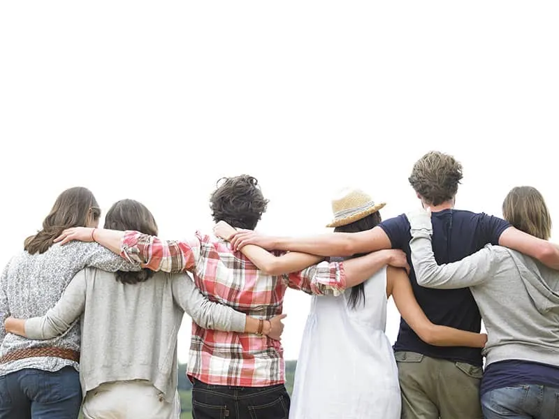 Rear view of group of friends hugging. Horizontal