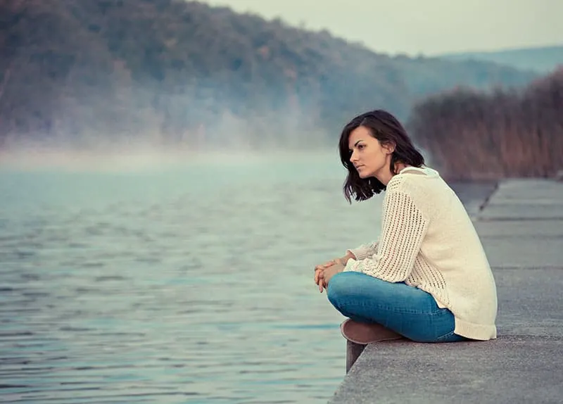 Girl sitting by lake 