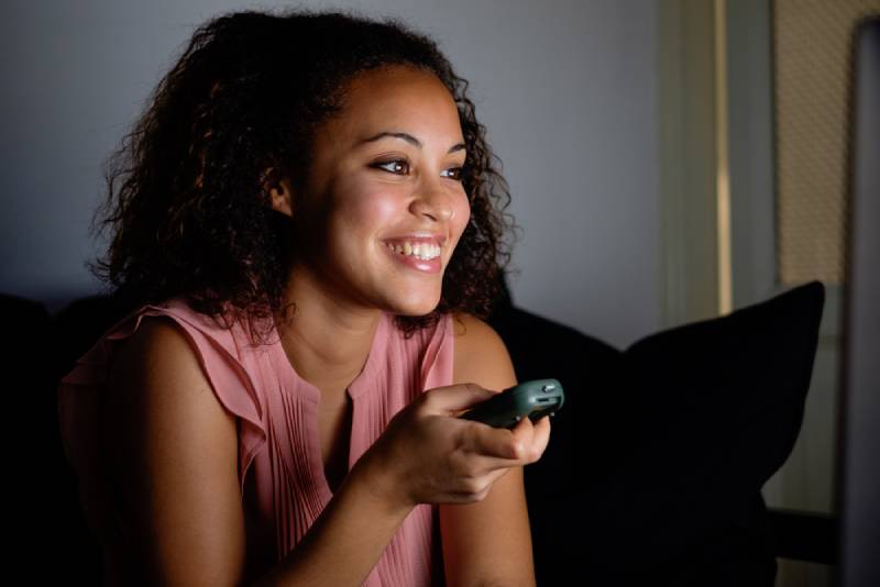 smiling woman watching TV at night