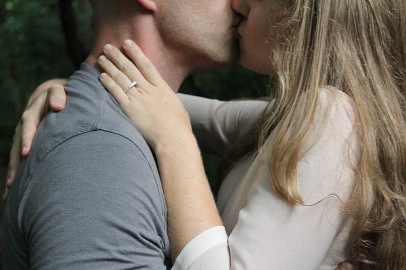 woman with engagement ring kissing man