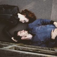 man and woman lying on concrete surface and looking each other