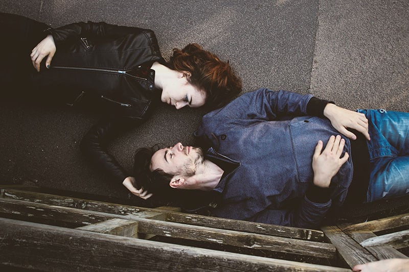 man and woman lying on concrete surface and looking each other